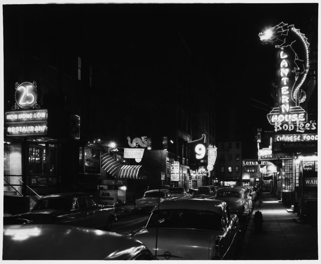 Night scene showing restaurant signs on Tyler Street with large numbers.