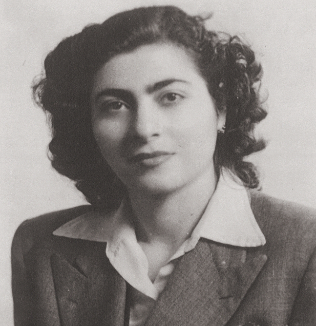 A portrait of a young woman looking at the camera. She wears a collared shirt and a blazer on top.