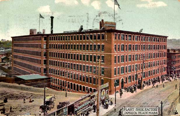 A postcard of a large, 6-story shoe factory next to a street with lots of pedestrians out front.