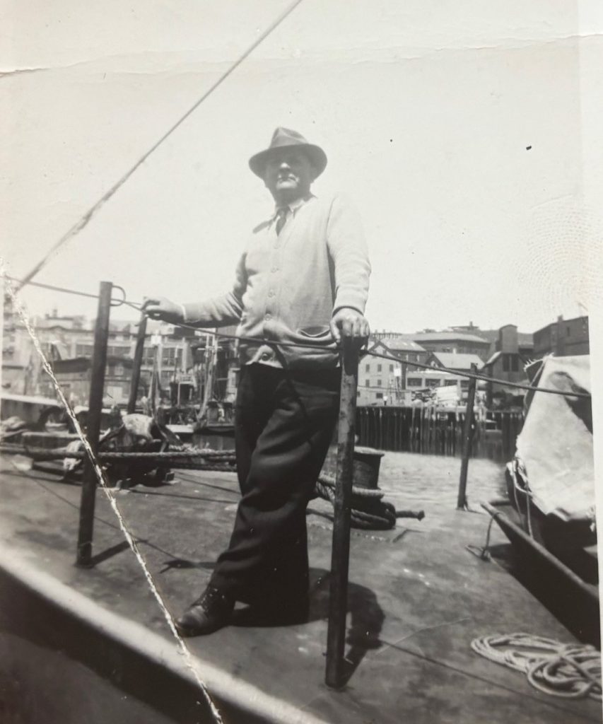 The author's grandfather standing on a wharf with houses in the background.