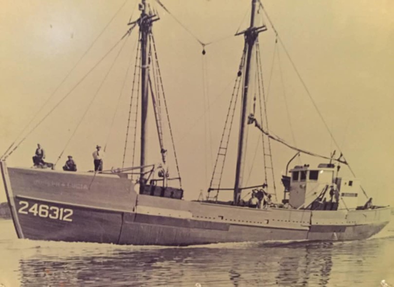 Fishing boat sailing with several crew members on board.